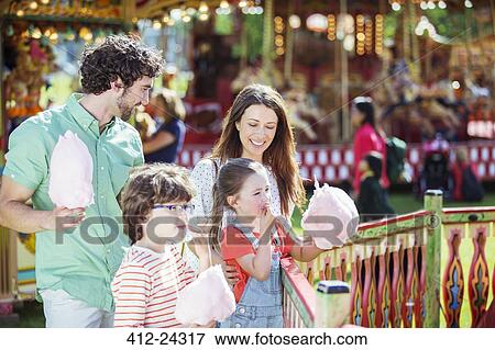 Stock Photo - Family with pink candy floss in amusement park. Fotosearch