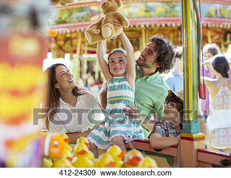 Girl holding teddy bear as trophy in fishing game in amusement park View Large Photo Image Stock Photo - Girl holding teddy bear as trophy in fishing game in amusement park. Fotosearch