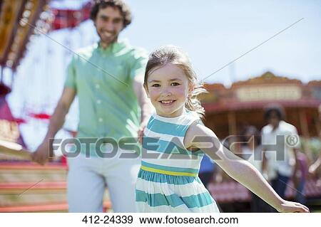 Stock Photo - Girl pulling her father in amusement park. Fotosearch