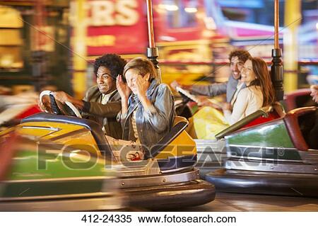 Stock Photography - Group of friends having fun on bumper car ride in amusement park. Fotosearch