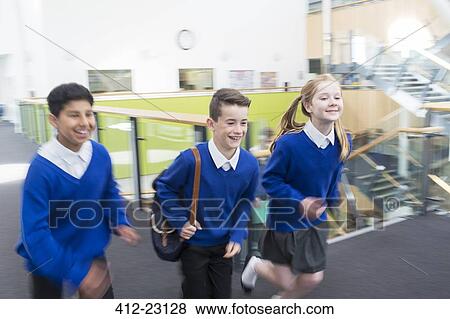 Happy pupils wearing school uniforms running in school corridor View Large Photo Image Stock Photo - Happy pupils wearing school uniforms running in school corridor. Fotosearch