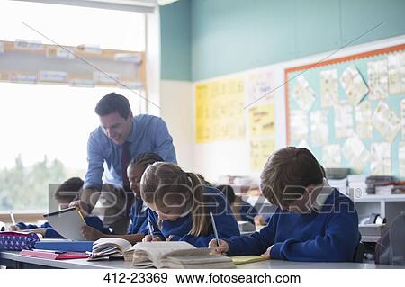Male teacher assisting elementary school children in classroom during lesson View Large Photo Image Stock Photo - Male teacher assisting elementary school children in classroom during lesson. Fotosearch