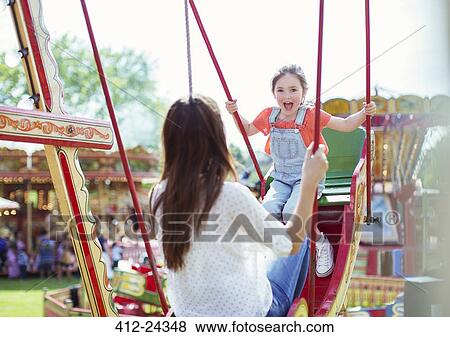 Stock Photo - Mother and daughter playing on swing in amusement park. Fotosearch