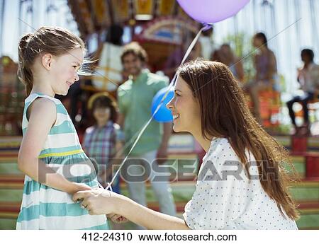 Mother and girl with balloon looking at each other in amusement park View Large Photo Image Stock Image - Mother and girl with balloon looking at each other in amusement park. Fotosearch