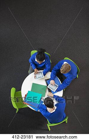 Overhead view of high school students sitting at round table with digital tablets View Large Photo Image Stock Image - Overhead view of high school students sitting at round table with digital tablets. Fotosearch