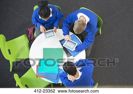 Overhead view of three students with digital tablets at round table View Large Photo Image Stock Image - Overhead view of three students with digital tablets at round table. Fotosearch
