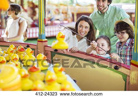 Parents with two children having fun with fishing game in amusement park View Large Photo Image Stock Image - Parents with two children having fun with fishing game in amusement park. Fotosearch