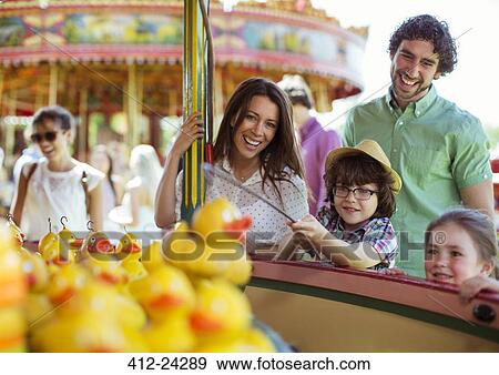 Parents with two children having fun with fishing game in amusement park View Large Photo Image Stock Photo - Parents with two children having fun with fishing game in amusement park. Fotosearch