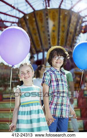 Portrait of boy and girl holding balloons in amusement park View Large Photo Image Stock Image - Portrait of boy and girl holding balloons in amusement park. Fotosearch