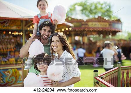 Portrait of cheerful family holding pink candy floss in amusement park View Large Photo Image Picture - Portrait of cheerful family holding pink candy floss in amusement park. Fotosearch