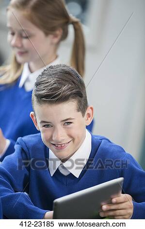 Portrait of cheerful schoolboy wearing blue school uniform with tablet pc in classroom View Large Photo Image Stock Photography - Portrait of cheerful schoolboy wearing blue school uniform with tablet pc in classroom. Fotosearch