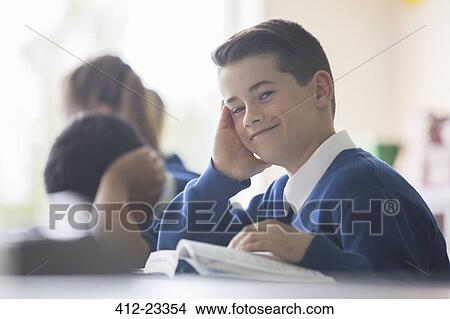 Portrait of smiling elementary school boy sitting at desk in classroom View Large Photo Image Picture - Portrait of smiling elementary school boy sitting at desk in classroom. Fotosearch