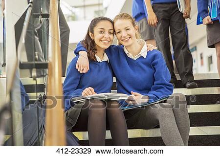 Portrait of two cheerful female students sitting on steps with arms around View Large Photo Image Stock Photo - Portrait of two cheerful female students sitting on steps with arms around. Fotosearch