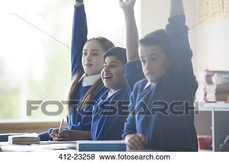 Primary school children in classroom raising arms View Large Photo Image Stock Photo - Primary school children in classroom raising arms. Fotosearch