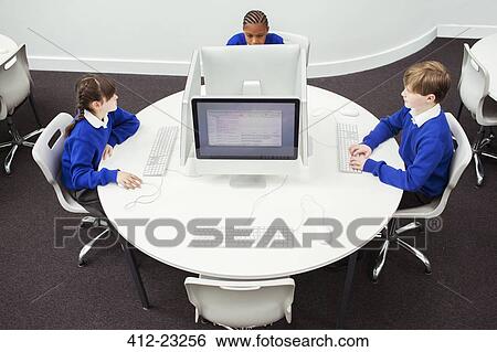 Stock Photograph - Primary school children working with computers during IT lesson. Fotosearch