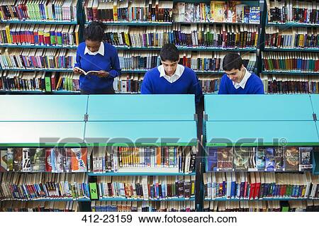 Stock Photo - Pupil learning in classroom using book and tablet pc. Fotosearch