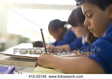 Pupils writing in notebooks at desks in classroom View Large Photo Image Stock Photography - Pupils writing in notebooks at desks in classroom. Fotosearch