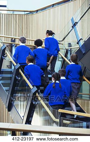 Rear view of group of pupils wearing blue school uniforms walking up stairs in school View Large Photo Image Stock Photo - Rear view of group of pupils wearing blue school uniforms walking up stairs in school. Fotosearch