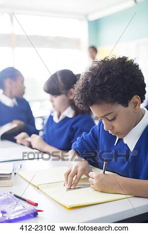 Schoolboy drawing in notebook at desk in classroom, girls in background View Large Photo Image Stock Image - Schoolboy drawing in notebook at desk in classroom, girls in background. Fotosearch