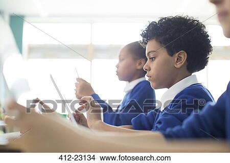 Schoolboys and schoolgirls sitting in classroom using tablet pc's View Large Photo Image Picture - Schoolboys and schoolgirls sitting in classroom using tablet pc's. Fotosearch