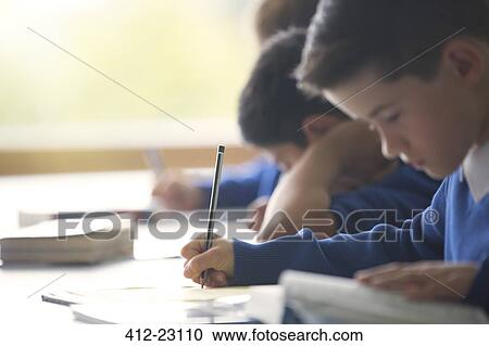 Schoolboys writing in notebook at desk in classroom View Large Photo Image Stock Image - Schoolboys writing in notebook at desk in classroom. Fotosearch