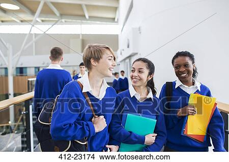 Smiling female students wearing school uniforms walking through school corridor View Large Photo Image Picture - Smiling female students wearing school uniforms walking through school corridor. Fotosearch