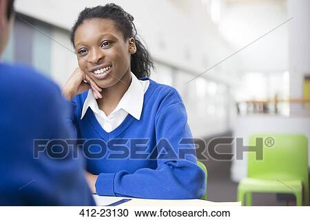 Smiling teenage student sitting at desk in school View Large Photo Image Stock Image - Smiling teenage student sitting at desk in school. Fotosearch