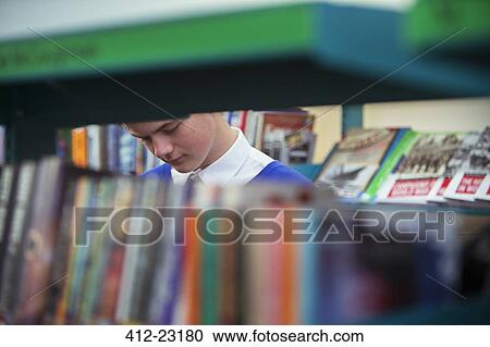 Student in library seen through book shelves View Large Photo Image Stock Image - Student in library seen through book shelves. Fotosearch