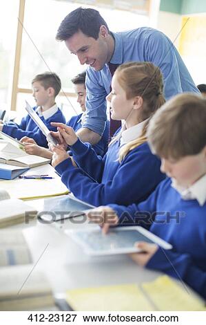 Teacher with his pupils in classroom using tablet pc View Large Photo Image Stock Photo - Teacher with his pupils in classroom using tablet pc. Fotosearch