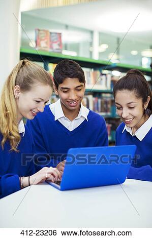 Three cheerful students working with laptop in library View Large Photo Image Stock Photograph - Three cheerful students working with laptop in library. Fotosearch