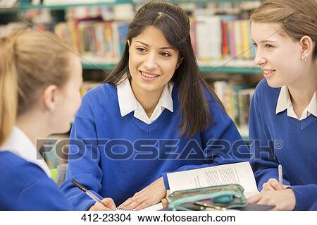 Picture - Three female students sitting in library and smiling. Fotosearch