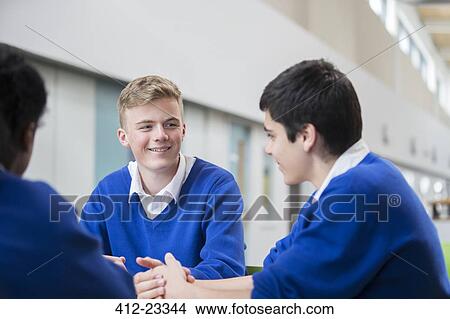 Three male students wearing blue school uniforms talking in corridor View Large Photo Image Picture - Three male students wearing blue school uniforms talking in corridor. Fotosearch