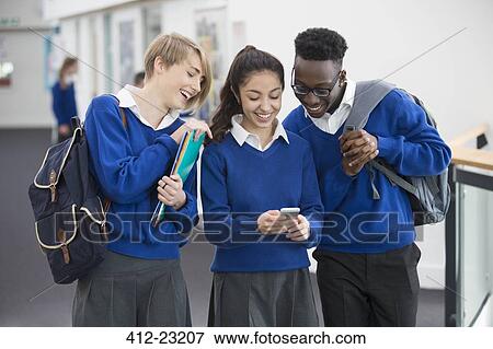 Three smiling students wearing blue school uniforms with mobile phone in school corridor View Large Photo Image Stock Photo - Three smiling students wearing blue school uniforms with mobile phone in school corridor. Fotosearch