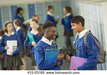 Stock Image - Two male students wearing school uniforms talking in locker room. Fotosearch