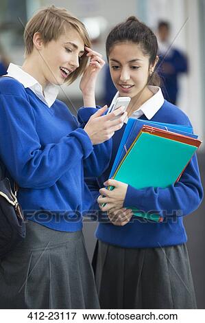 Stock Photo - Two smiling female students wearing school uniforms using smartphone. Fotosearch