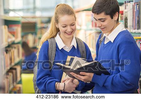 Two smiling high school students wearing school uniforms looking at book in library View Large Photo Image Stock Photograph - Two smiling high school students wearing school uniforms looking at book in library. Fotosearch