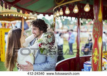 Woman holding bouquet and embracing his boyfriend in amusement park View Large Photo Image Stock Image - Woman holding bouquet and embracing his boyfriend in amusement park. Fotosearch