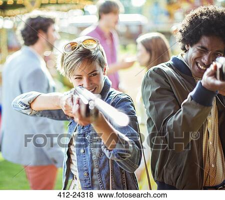 Young couple aiming with guns in amusement park View Large Photo Image Stock Photo - Young couple aiming with guns in amusement park. Fotosearch