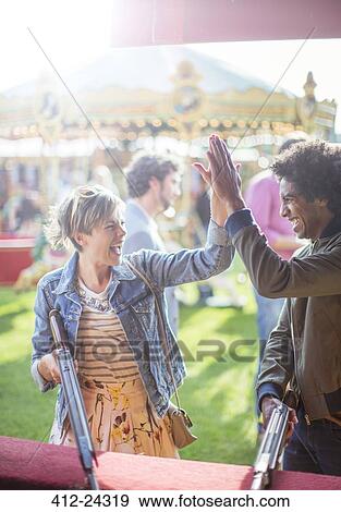 Stock Photo - Young couple giving high five in amusement park. Fotosearch