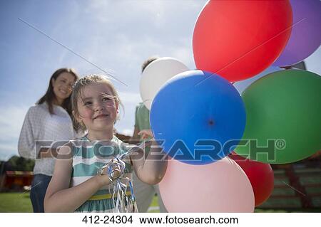 Young girl holding bunch of colorful balloons at sunny day View Large Photo Image Picture - Young girl holding bunch of colorful balloons at sunny day. Fotosearch