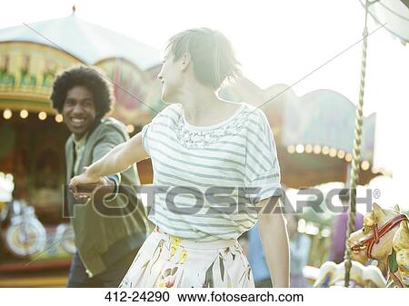 Stock Image - Young multiracial couple having fun in amusement park. Fotosearch