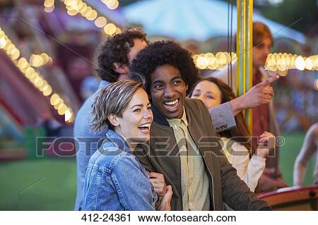 Stock Image - Young multiracial couple having fun in amusement park. Fotosearch