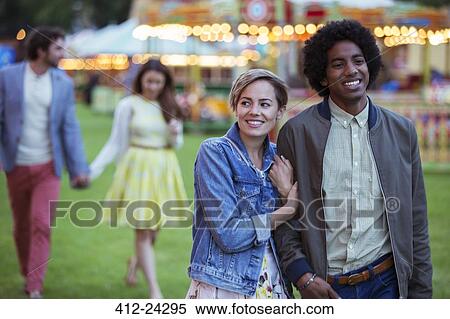 Young multiracial couple smiling while walking in amusement park View Large Photo Image Stock Photography - Young multiracial couple smiling while walking in amusement park. Fotosearch