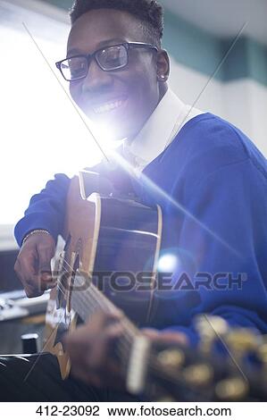 Young student playing acoustic guitar in classroom View Large Photo Image Stock Image - Young student playing acoustic guitar in classroom. Fotosearch