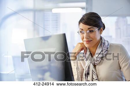 Female office worker sitting at desk using computer View Large Photo Image Picture - Female office worker sitting at desk using computer. Fotosearch