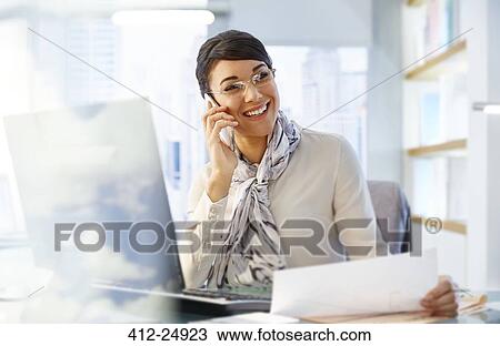 "Female office worker sitting at desk using smartphone, working" View Large Photo Image Stock Image - "Female office worker sitting at desk using smartphone, working". Fotosearch