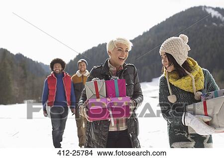 Friends carrying Christmas gifts in snow View Large Photo Image Picture - Friends carrying Christmas gifts in snow. Fotosearch