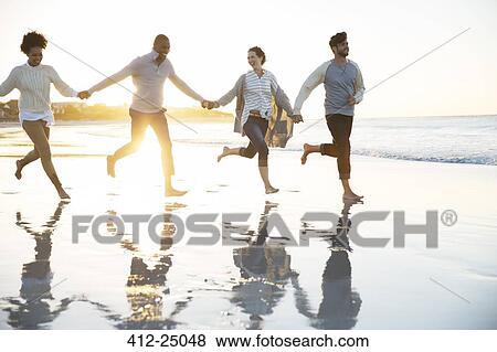 Group of four friends holding hands and running on beach View Large Photo Image Stock Photo - Group of four friends holding hands and running on beach. Fotosearch
