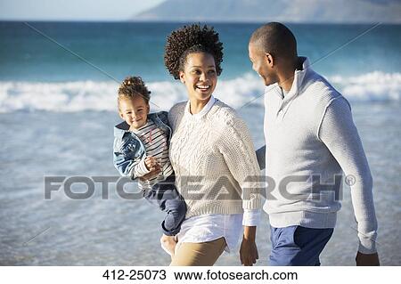 Stock Image - Happy family having fun on beach. Fotosearch