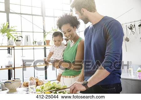 Happy family preparing meal in domestic kitchen View Large Photo Image Picture - Happy family preparing meal in domestic kitchen. Fotosearch